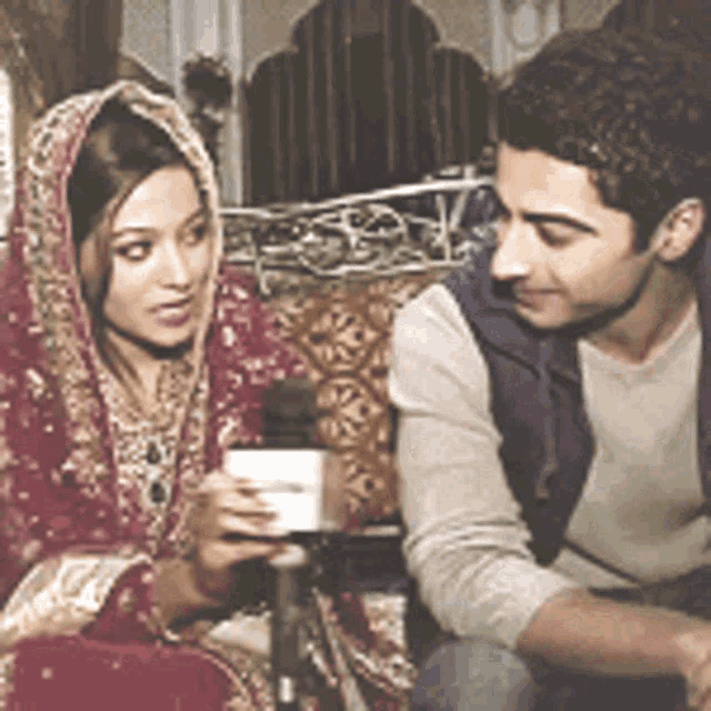 a man and a woman are sitting next to each other talking into a microphone .
