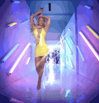 a woman in a yellow dress is dancing in a hallway with neon lights