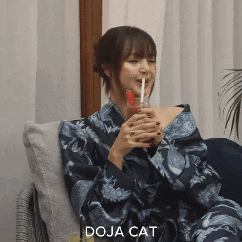 a woman in a kimono is drinking through a straw and the word doja cat is next to her