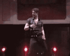 a man is dancing on a stage with red lights