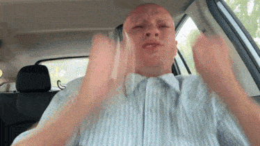 a man in a striped shirt is sitting in a car