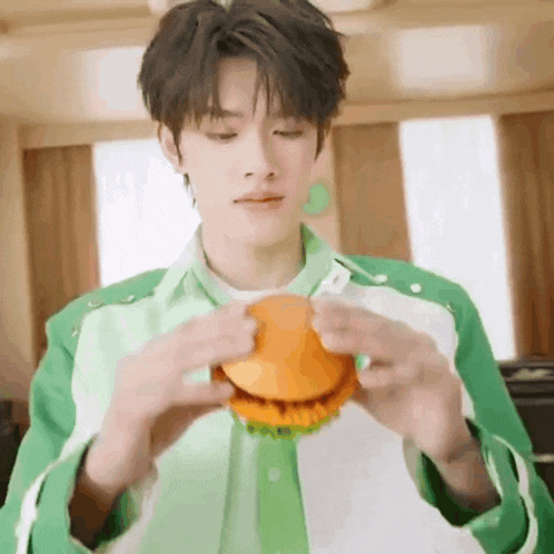a young man is holding a hamburger in his hands .