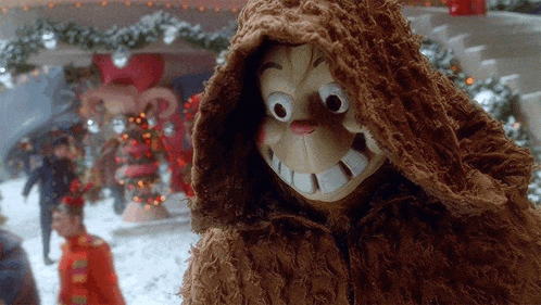 a stuffed animal wearing a hooded jacket with a big smile on his face .
