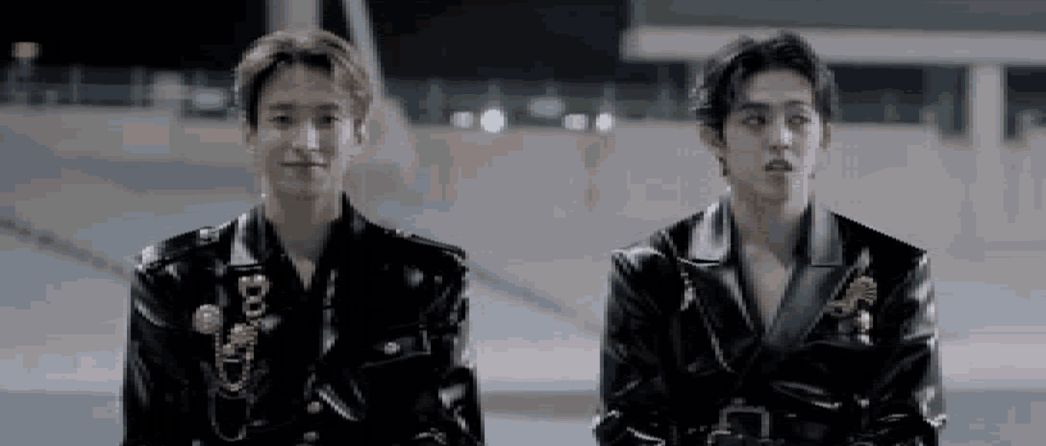 two young men are standing next to each other wearing black leather jackets .