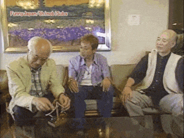 a group of older men are sitting around a table with funny japan written on the bottom right
