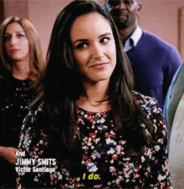 a woman in a floral shirt says i do in front of a group of people