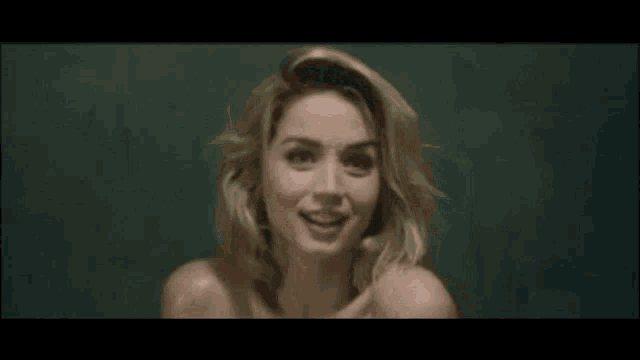 a woman without a shirt is looking at the camera and smiling