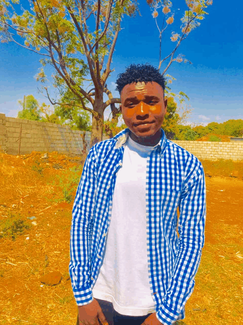 a man wearing a plaid shirt and a white shirt poses for a picture