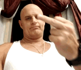 a bald man in a white tank top is giving the middle finger to the camera