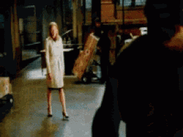 a woman in a white coat is standing next to a man carrying a box with the number 16 on it