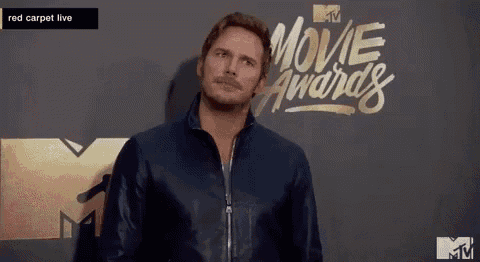 a man with a mustache is standing in front of a wall that says movie awards .