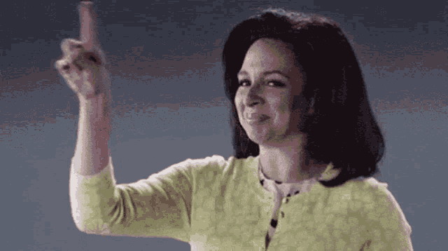 a woman in a yellow sweater is making a middle finger gesture .