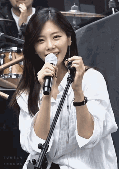a woman singing into a microphone with tumblr written on the bottom right corner