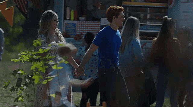 a man and a woman are holding hands in front of a crowd of people