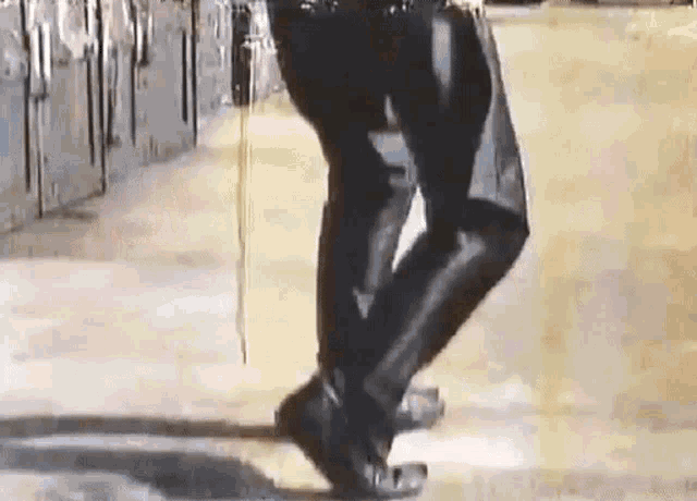 a person is walking down a sidewalk wearing black boots and a black jacket .