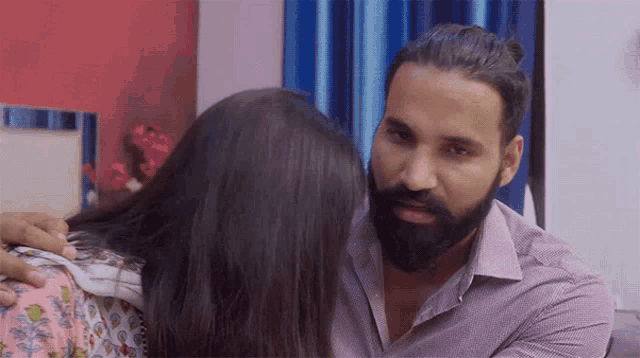 a man with a beard is hugging a woman with long hair