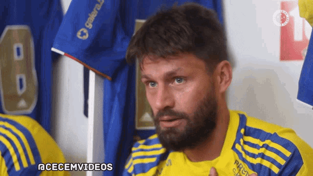 a man with a beard wearing a yellow and blue jersey that says aceemvideos