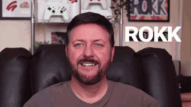 a man with a beard is sitting in a chair with rokk written in white