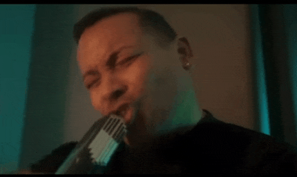 a man is singing into a microphone in a dark room in a dark room .