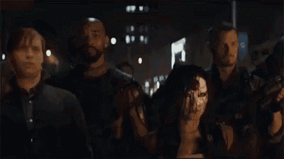 a group of people are standing in a dark room holding guns .