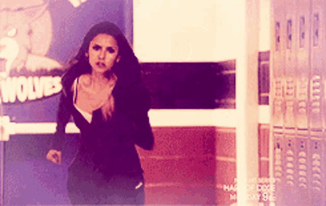 a woman is running in front of a poster that says wolves