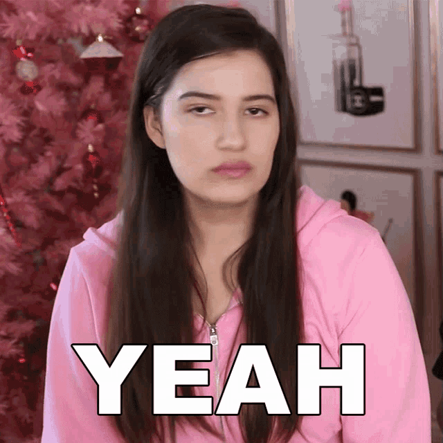 a woman in a pink hoodie says yeah in front of a pink tree