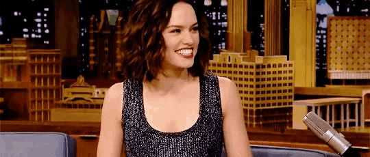a woman with curly hair is smiling while sitting in front of a microphone