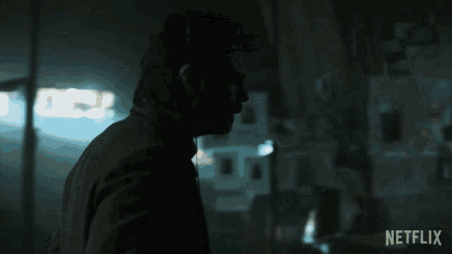 a man wearing headphones is standing in a dark room with a netflix logo on the bottom right