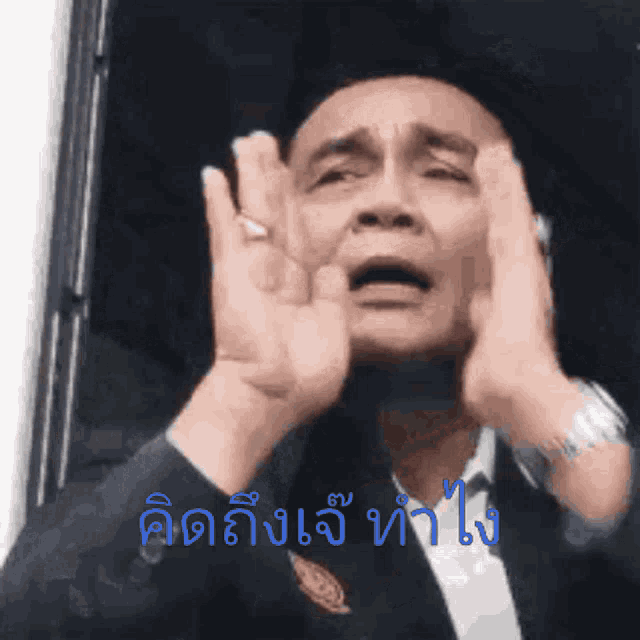 a man in a suit is making a funny face with his hands in front of his face