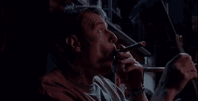 a man is smoking a cigarette in a dark room while sitting on the floor .