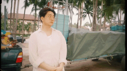 a man in a white shirt stands in front of a trailer