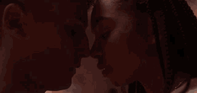 a man and woman are kissing in a dark room .