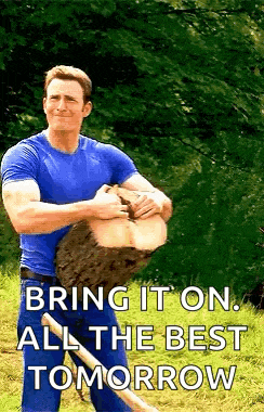 a man in a blue shirt is holding a large log and a shovel in his hands .
