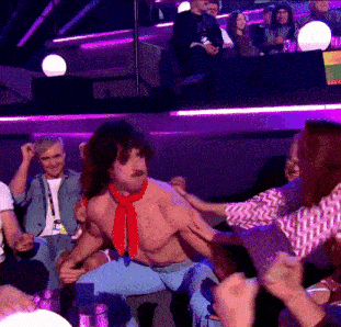 a shirtless man with a red scarf around his neck is being helped by a woman