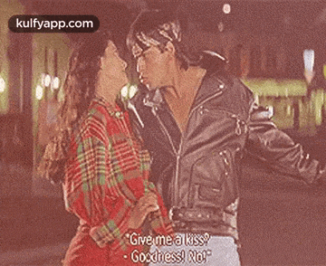 a man in a leather jacket is kissing a woman in a plaid shirt on the cheek .