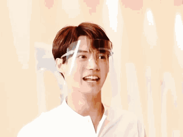 a young man wearing a face shield is smiling with his eyes closed