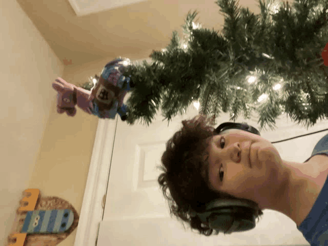 a boy wearing headphones is standing next to a christmas tree