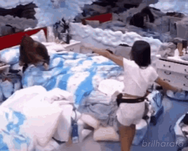 a woman is standing in front of a messy bedroom with a bed .