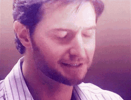 a close up of a man with a beard wearing a striped shirt with his eyes closed .