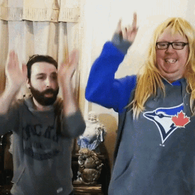 a man and a woman wearing blue jays sweatshirts are dancing together