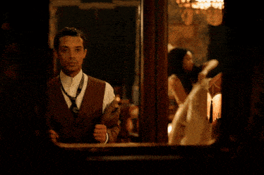 a man in a suit and tie adjusts his tie in front of a mirror