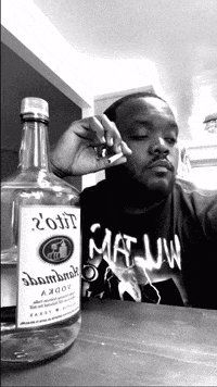 a man smoking a cigarette next to a bottle that says ' 2011 ' on it