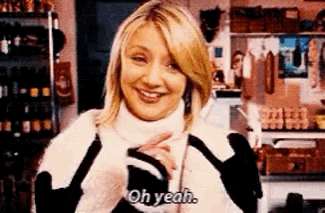 a woman wearing a turtleneck sweater is smiling and says oh yeah .