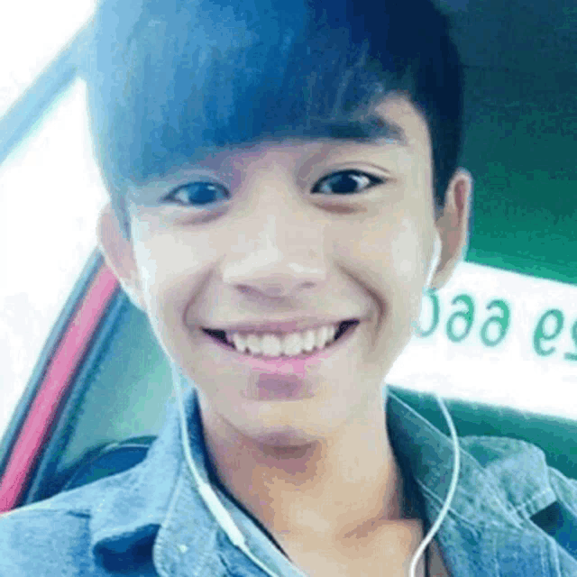 a young man wearing ear buds is smiling for the camera
