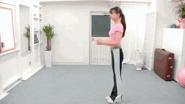 a woman in a pink shirt is standing in a room