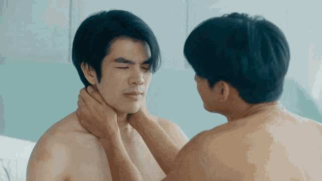 a shirtless man is being touched by another man