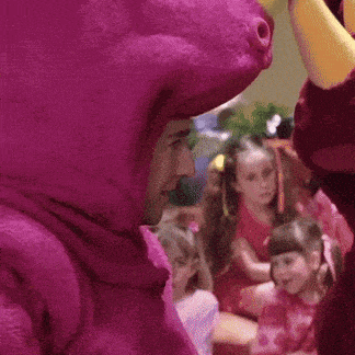 a person in a purple costume is standing next to a mascot .