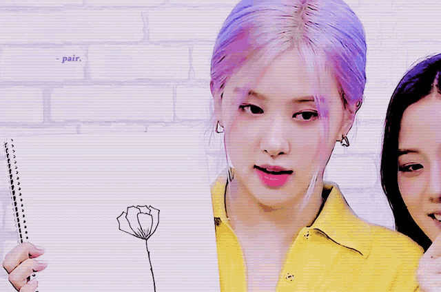 a woman with purple hair is holding a notebook with a flower drawn on it