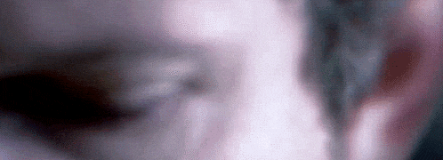 a close up of a person 's face with a blurry background and a purple eye .