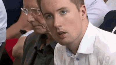 a man in a white shirt is sitting in a row of people .